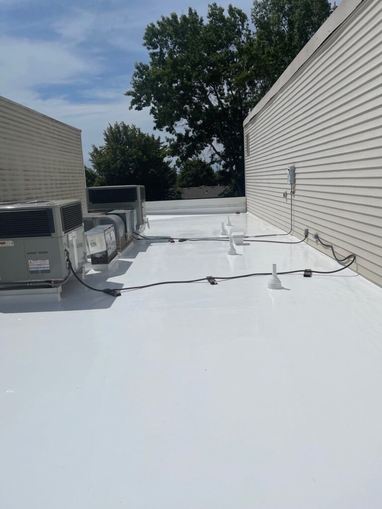 Crew applying a reflective roof coating to a low‑slope commercial roof during a roof restoration project.